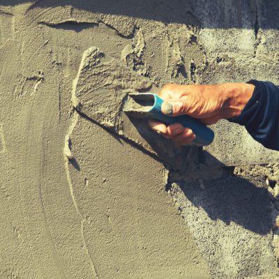 hand of worker plastering cement on wall